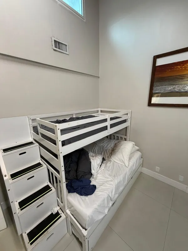 Bunk bed with unmade sheets and clothes before cleaning