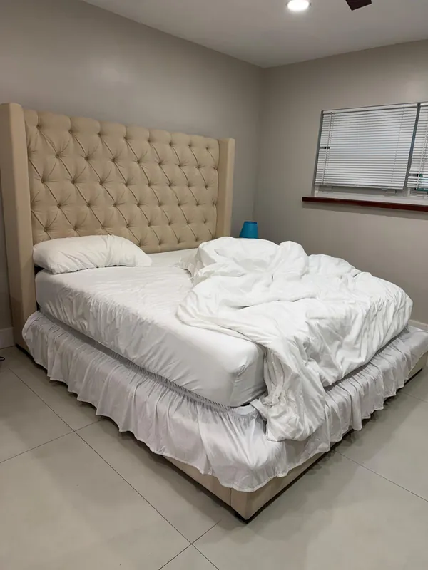 Bedroom with an unmade queen bed before cleaning