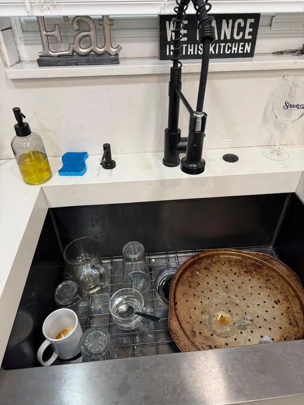 Kitchen sink full of dirty dishes and glasses before cleaning