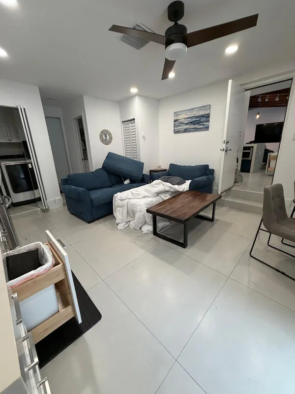 Living room with a blanket on the sofa and an open trash bin before cleaning